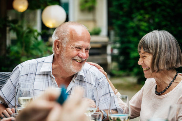 An elderly couople smiling and drinking at a family barbecue in a courtyard.